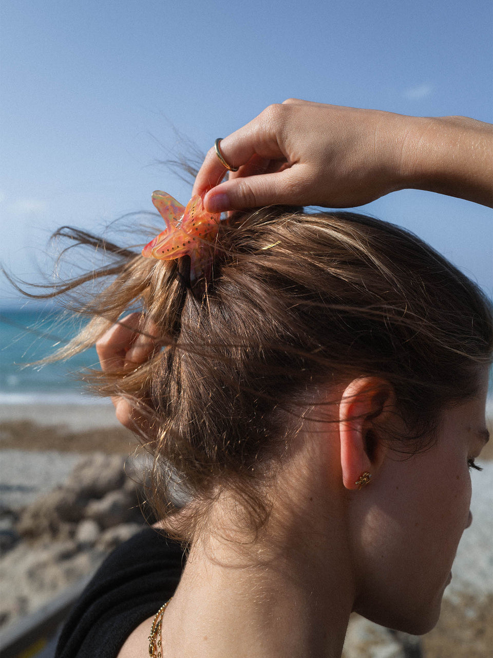 Starfish Haarklammer von PURELEI aus orangefarbenem Acetat mit goldenen Punkten im natürlichen Strandambiente