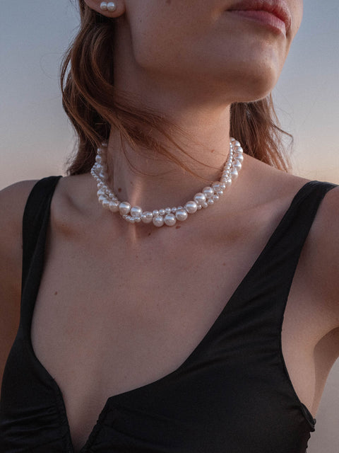 PURELEI Pearl Elegance Perlenkette aus Muschelperlen, getragen mit elegantem Schwarz, strahlt feminine Leichtigkeit aus.