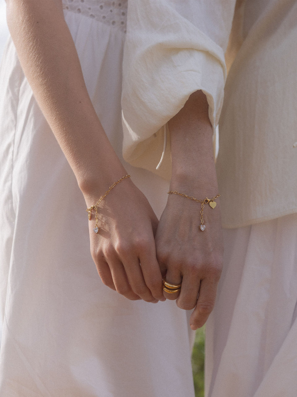 Endless Love Armband-Set von PURELEI, 18K vergoldet, mit Herzanhängern und Zirkonia, zart am Handgelenk getragen.