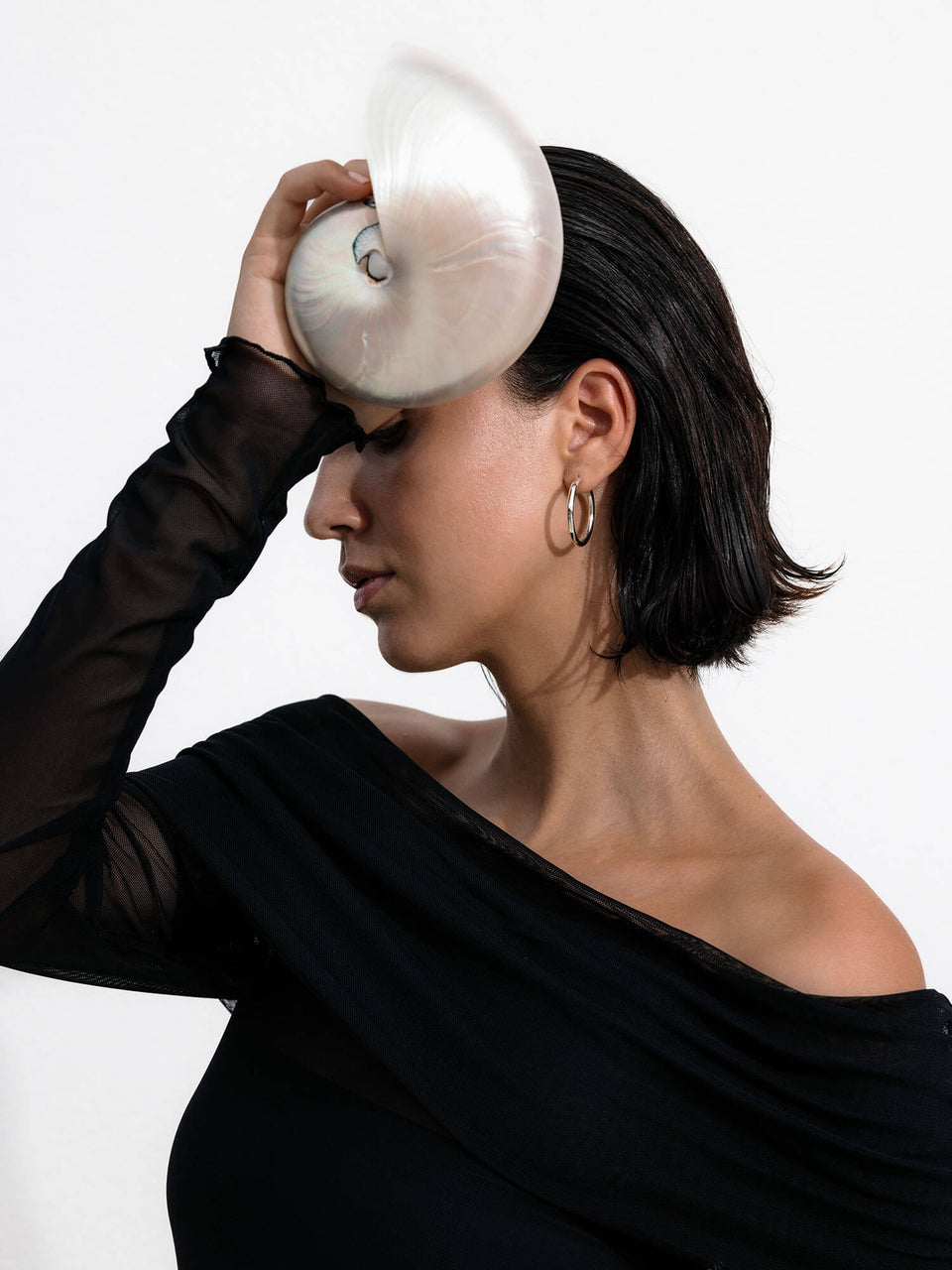 PURELEI Timeless Ohrringe aus glänzendem Silber, minimalistisch elegant am Ohr einer Frau mit schwarzem Oberteil.