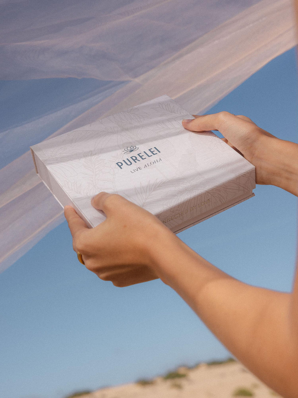 PURELEI Geschenkbox M in Beige mit Magnetverschluss und zartem Pflanzenmuster vor blauem Himmel