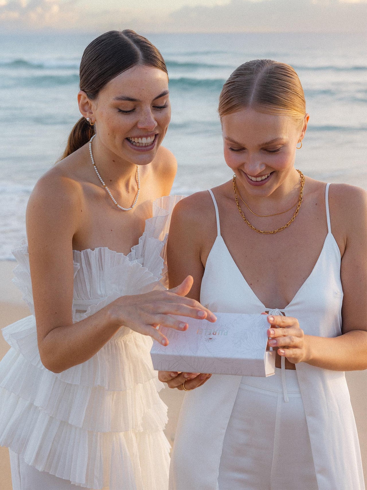 Geschenkbox S von PURELEI in Beige mit dezentem Pflanzenmuster, Magnetverschluss und edlem Logoschriftzug am Strand.