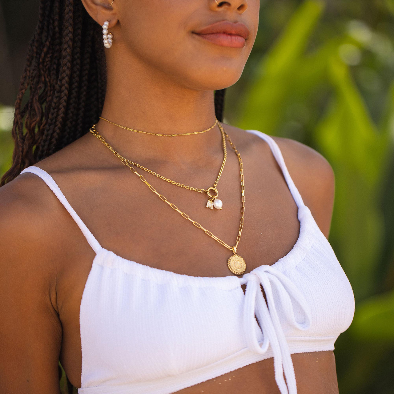 Maikai Charm Kette in 18K Gold, schlicht und elegant, getragen vor grünem Naturhintergrund, PURELEI.