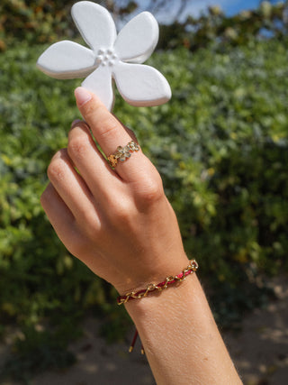 Roségoldenes Blumenring und Armband von PURELEI, umgeben von tropischer Natur.