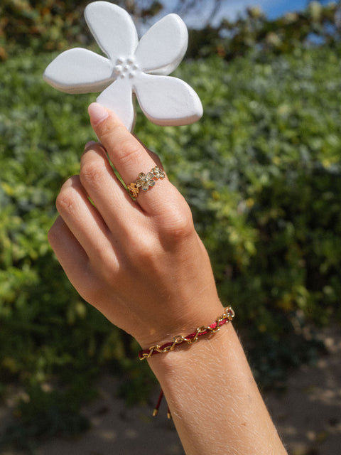 Roségoldenes Blumenring und Armband von PURELEI, umgeben von tropischer Natur.