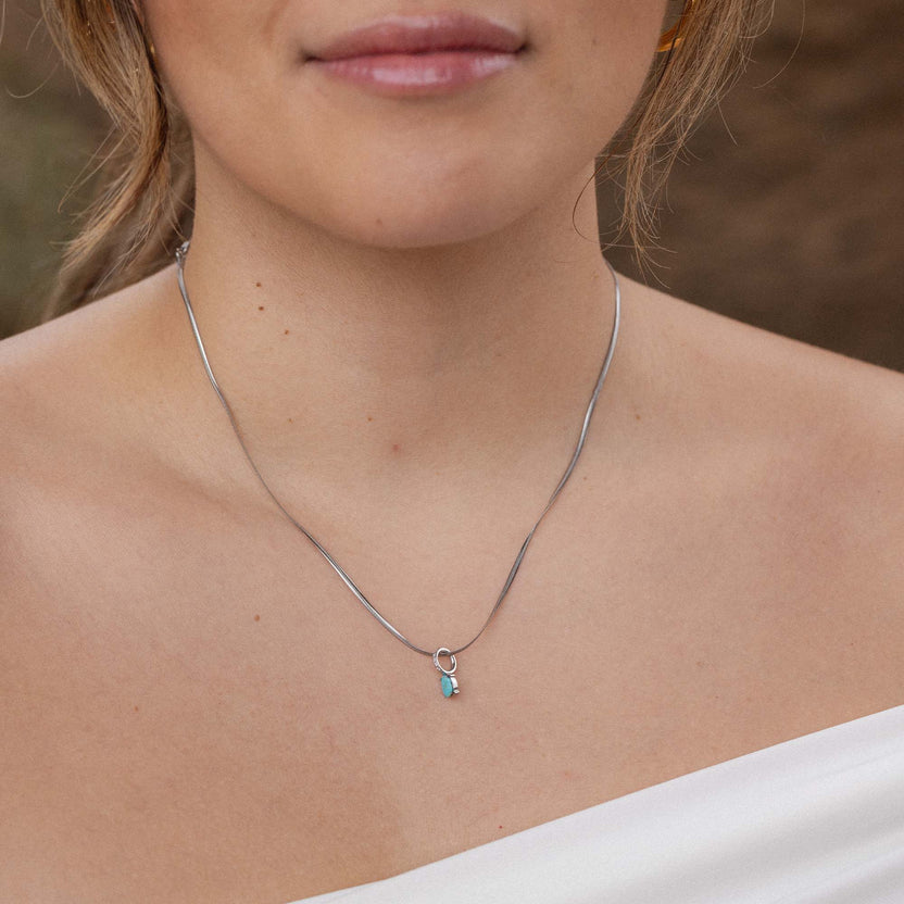 Silberne Kette mit zartem Anhänger, getragen auf nackter Haut, PURELEI.