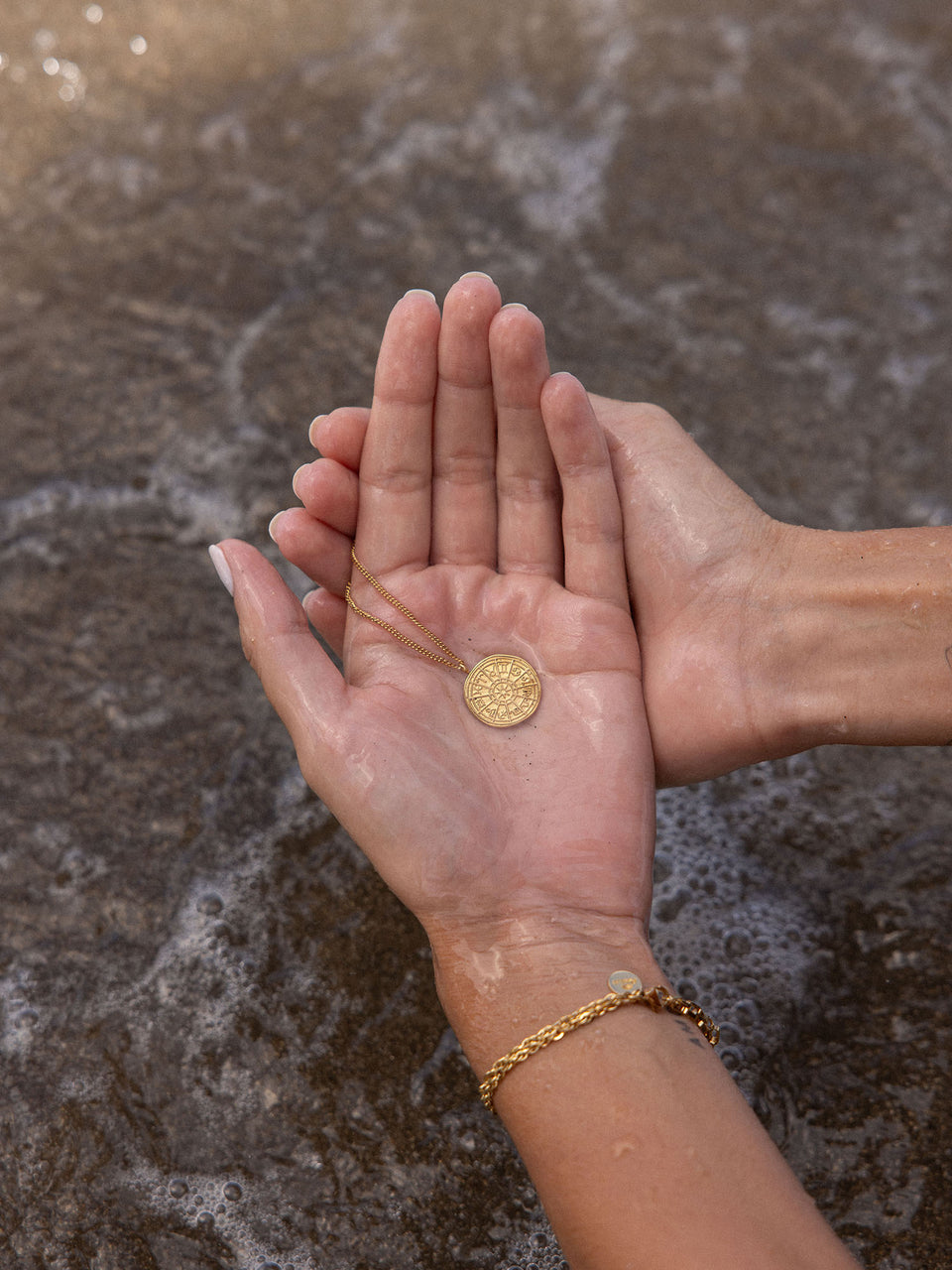 PURELEI Zodiac Kette aus 18K Gold Edelstahl, zart in Händen über Wasser gehalten, strahlt elegante Magie aus.
