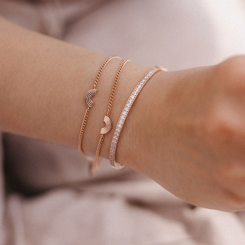 Drei roségoldene Armbänder mit funkelnden Details, getragen von PURELEI.