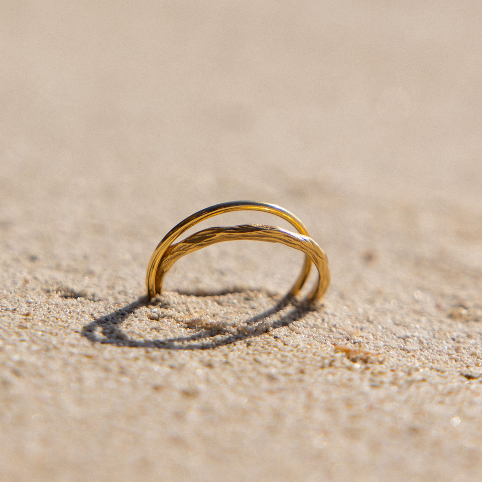 Double Match Anxiety Ring von PURELEI – 18K vergoldete, ineinander verschlungene Ringe im warmen Sand mit sonniger Leichtigkeit.