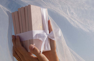 Zarte, rosa Geschenkbox mit weißem Band, gehalten in sanften Händen – PURELEI Aloha-Vibes.