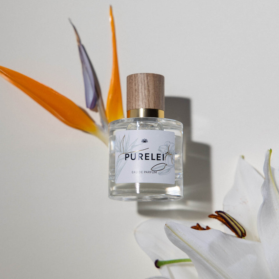 PURELEI Eau de Parfum 50ml mit Holzdeckel, blumig-zitrisch, inszeniert neben tropischer Blüte, elegant.