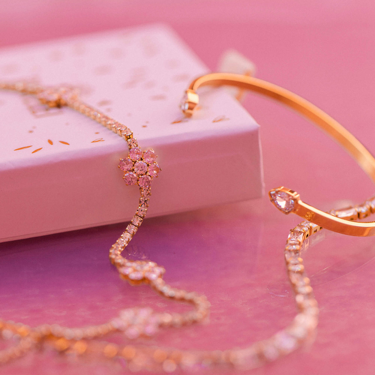 Anima Kette von PURELEI in 18K Roségold mit rosa Zirkonia-Blüten, elegant inszeniert auf zartem rosa Hintergrund.