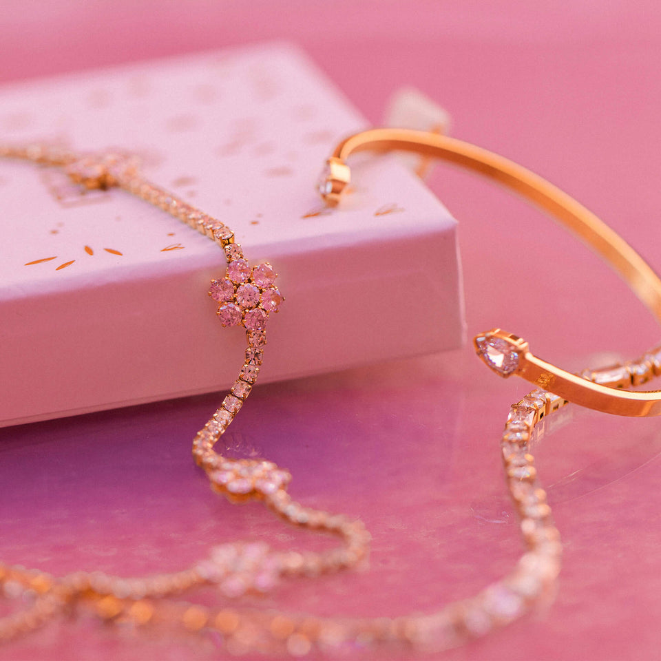 Anima Kette von PURELEI in 18K Roségold mit rosa Zirkonia-Blüten, elegant inszeniert auf zartem rosa Hintergrund.