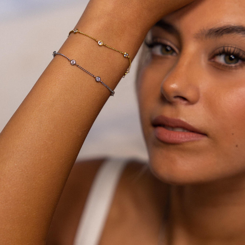 Zwei zarte Armbänder aus Roségold mit funkelnden Steinen, getragen von einer Frau, PURELEI.
