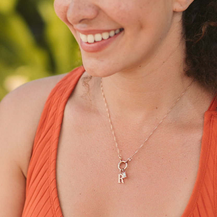 PURELEI Pure R Charm Anhänger aus 18K Roségold vergoldetem Edelstahl, elegant und feminin getragen am Dekolleté.