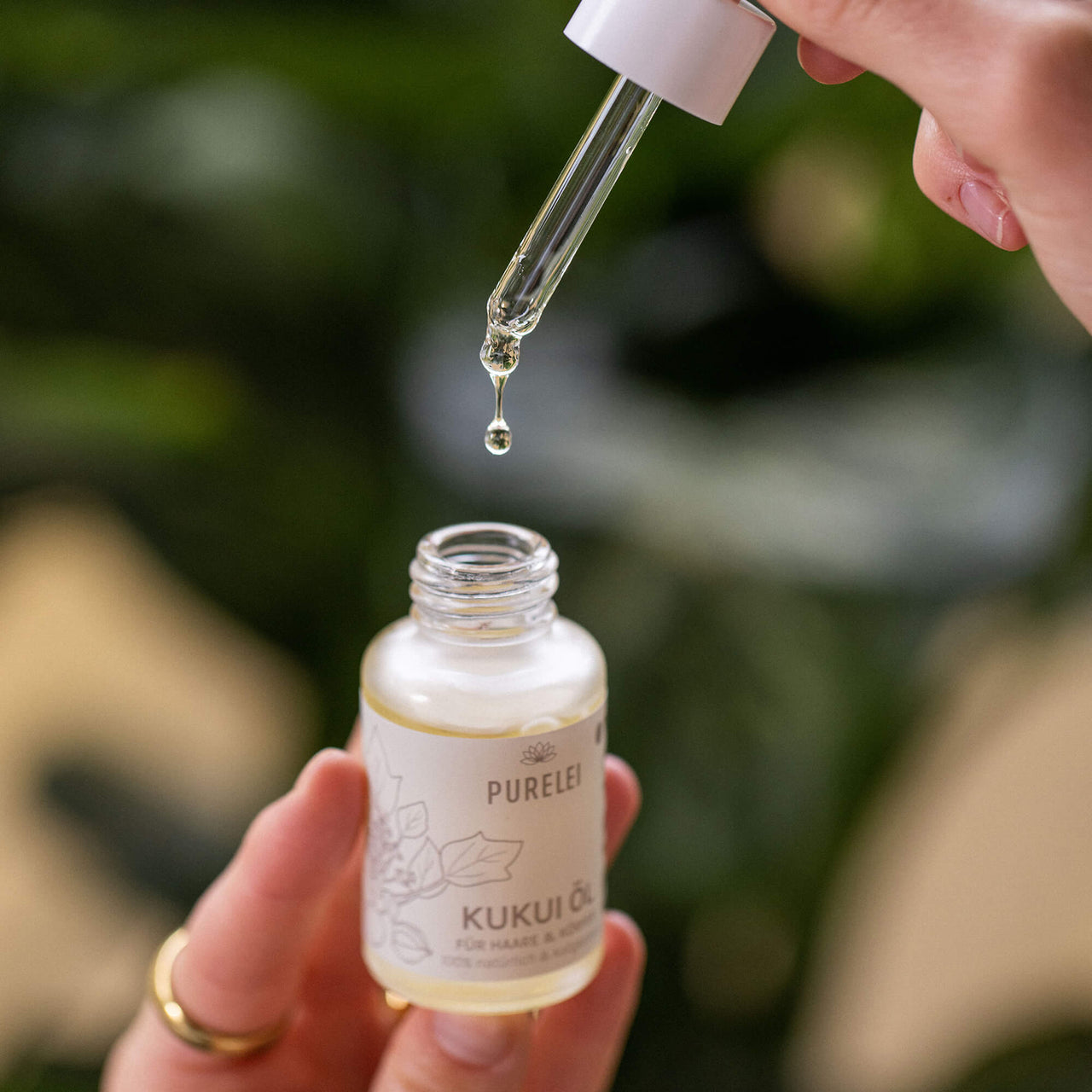 Klares, flüssiges Kukui Haar und Hautöl in Glasflasche, gehalten mit warmem Island-Spirit, PURELEI Exclusiv.
