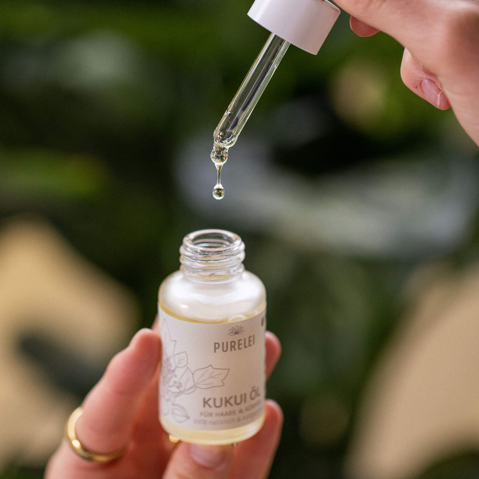 Klares, flüssiges Kukui Haar und Hautöl in Glasflasche, gehalten mit warmem Island-Spirit, PURELEI Exclusiv.