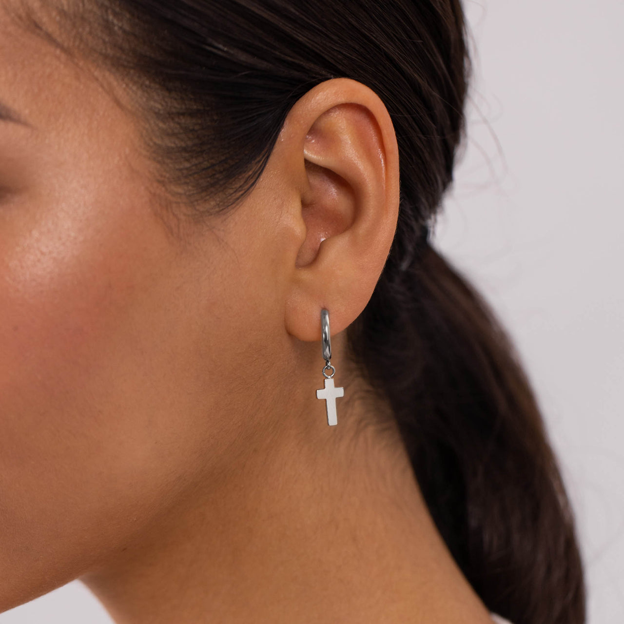 Cross Creole Ohrringe in nickelfreiem Silber mit Kreuzanhänger, elegant am Ohr getragen von PURELEI.
