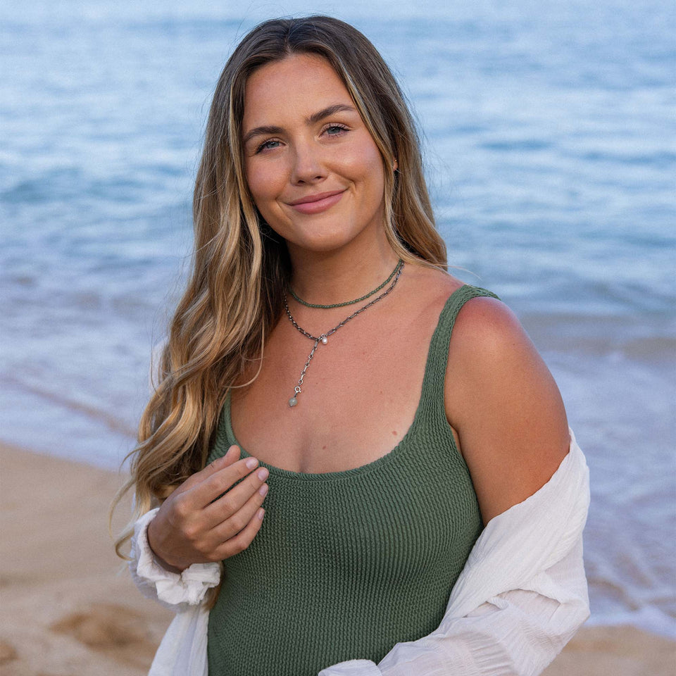 PURELEI Aventurine Charm in Gold mit grünem Aventurin, getragen am Strand, strahlt natürliche Eleganz und Ruhe aus.