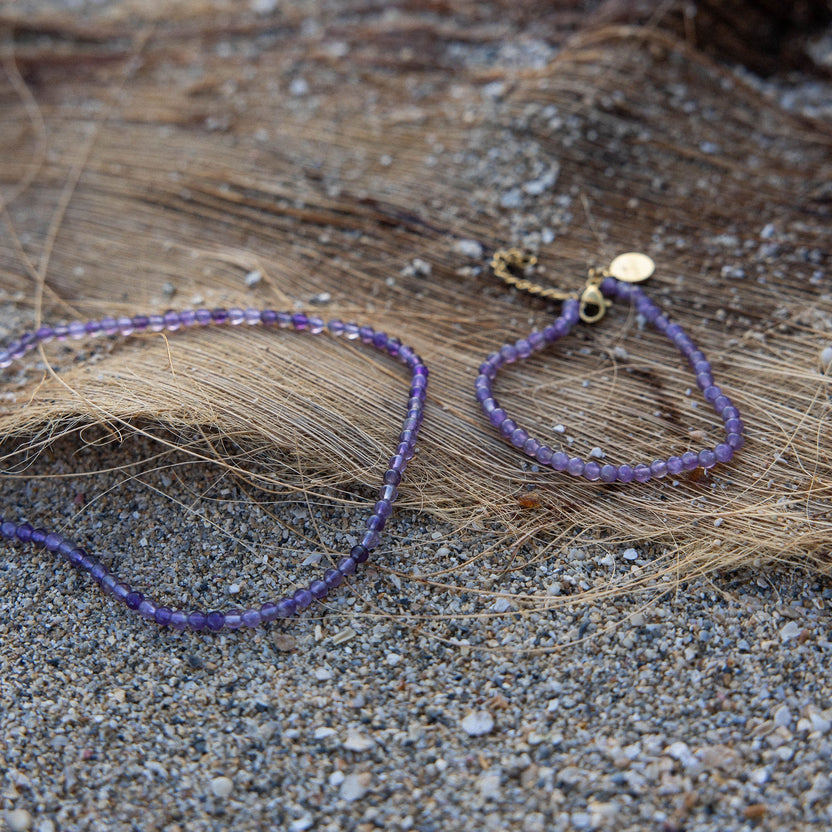 Amethyst Armband von PURELEI auf Strand mit warmem Licht, zarte lila Edelsteinperlen, elegant und natürlich.