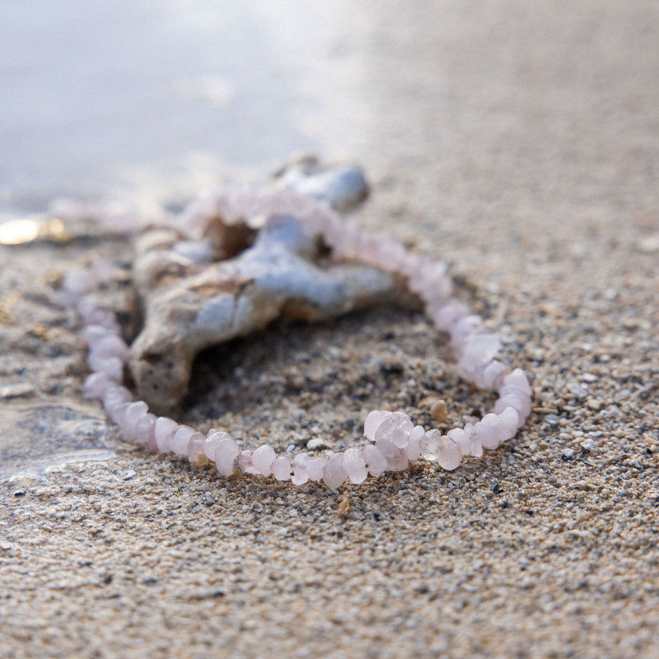 PURELEI Rosenquarz Kette mit zarten rosa Steinen am Strand, natürlich und elegant, nickelfrei und wasserfest.