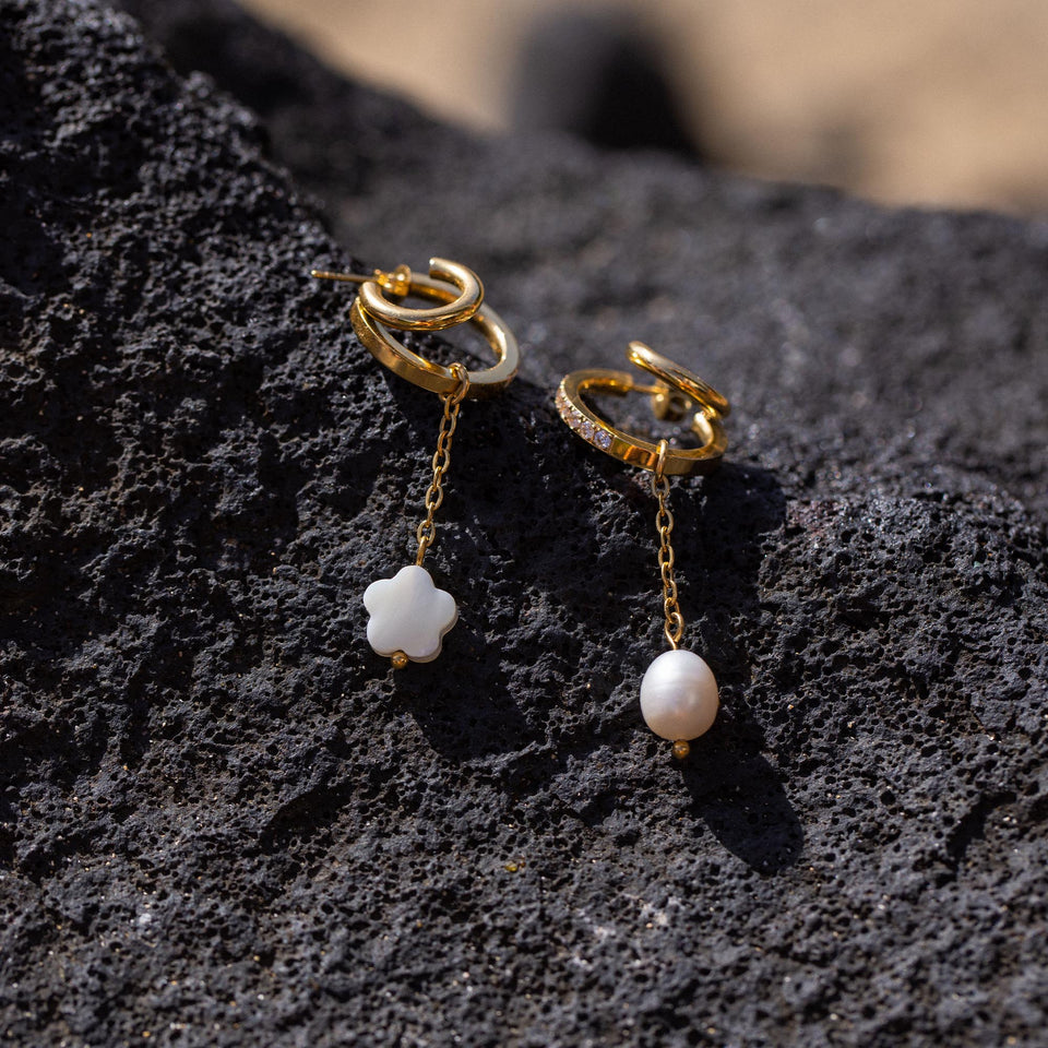 PURELEI Pearl Drop Charm mit goldener Kette und weißer Süßwasserperle auf dunklem Lavagestein, elegant und feminin