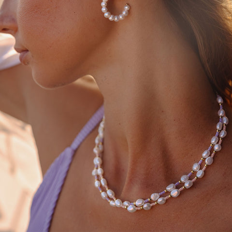 Nakala Kette von PURELEI mit pastellfarbenen Perlen in warmem Sonnenlicht, elegant und feminin am Hals getragen.
