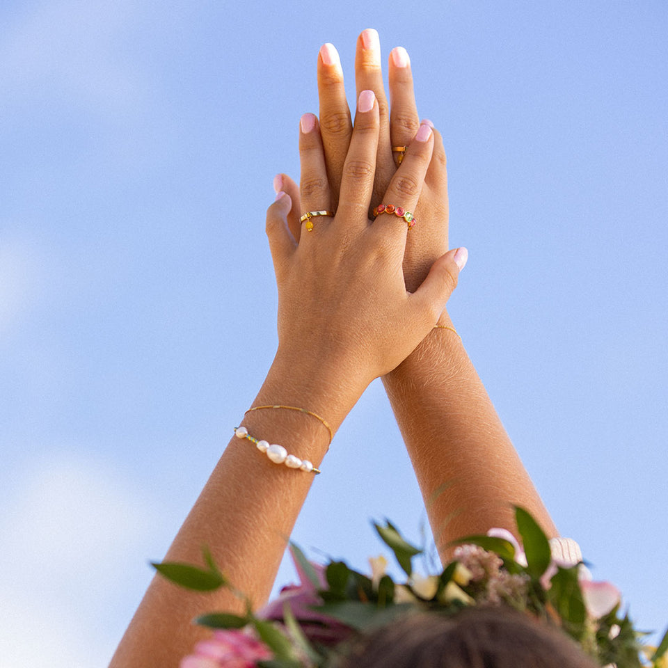 Blissful Armband von PURELEI mit Süßwasserperlen und Edelstahl vergoldet, sommerlich am Handgelenk vor blauem Himmel