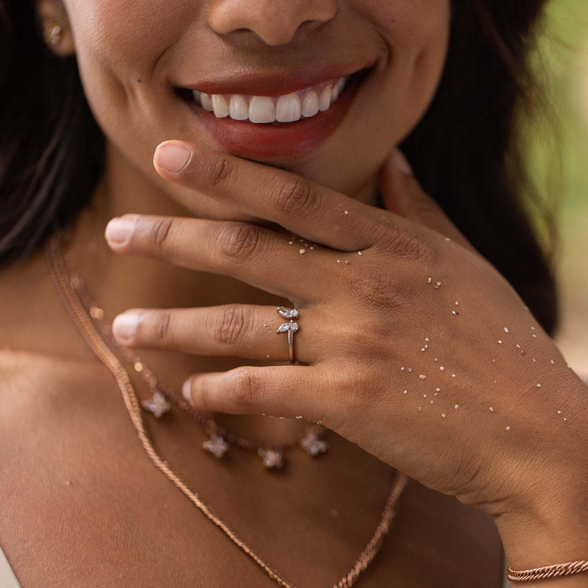 Zarte, roségoldene PURELEI Kette und Ring mit funkelnden Details, getragen mit strahlendem Lächeln.