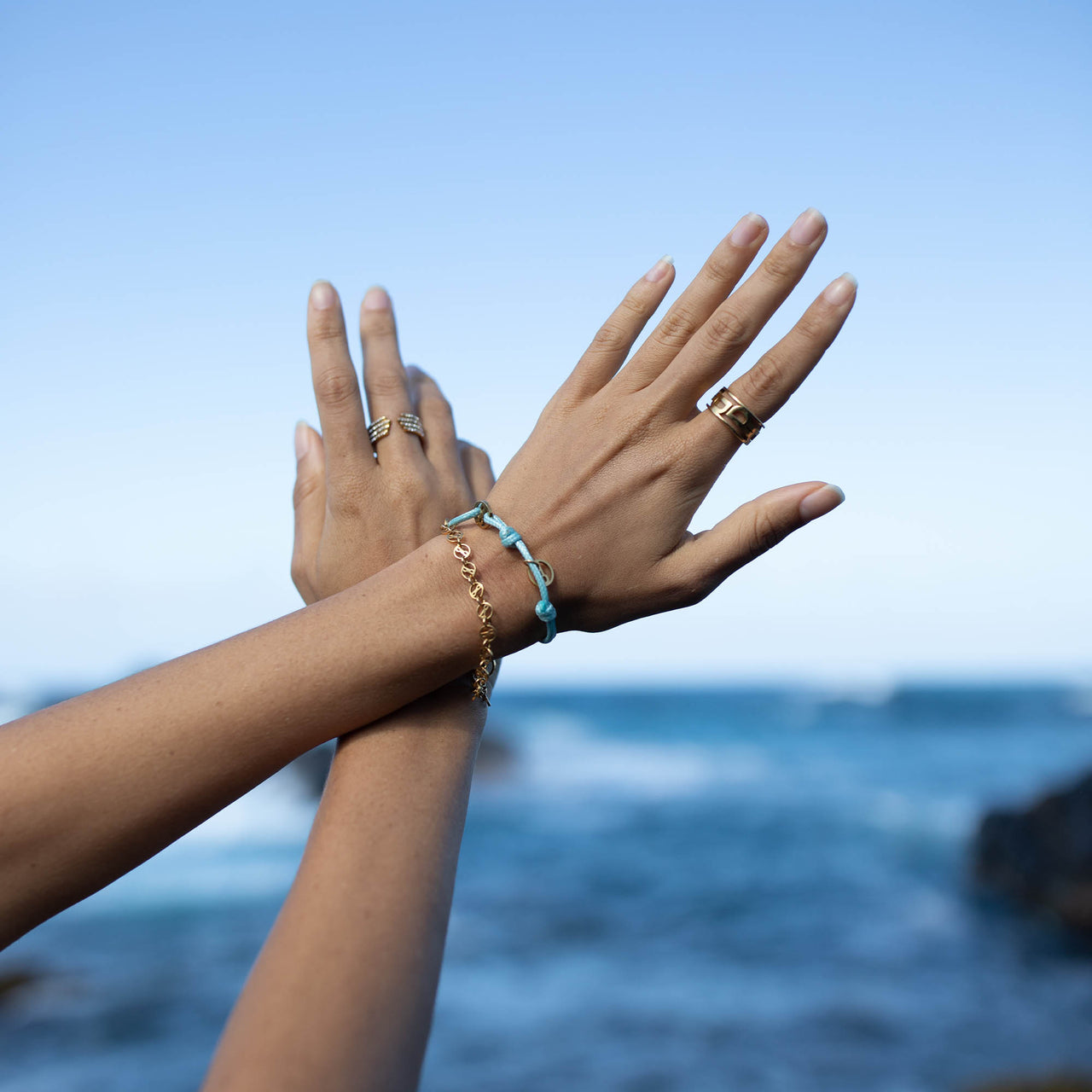 Phenomenal Armband von PURELEI in vergoldetem Edelstahl, getragen vor blauem Meer, elegant und zeitlos gestaltet.