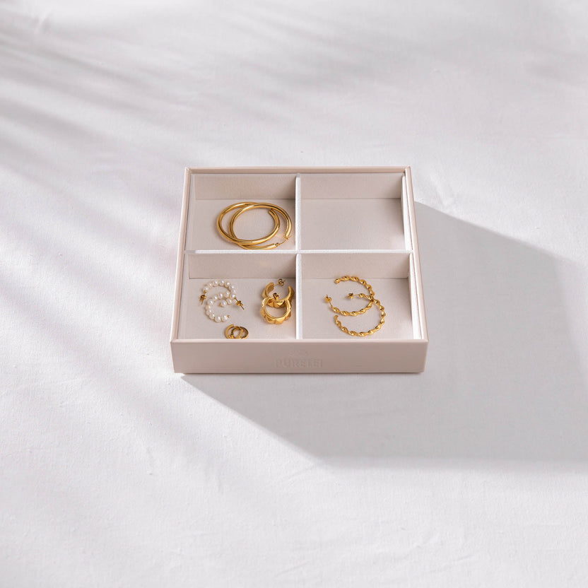 Elegante PURELEI Schmuckbox mit goldenen Accessoires auf hellem Stoff.