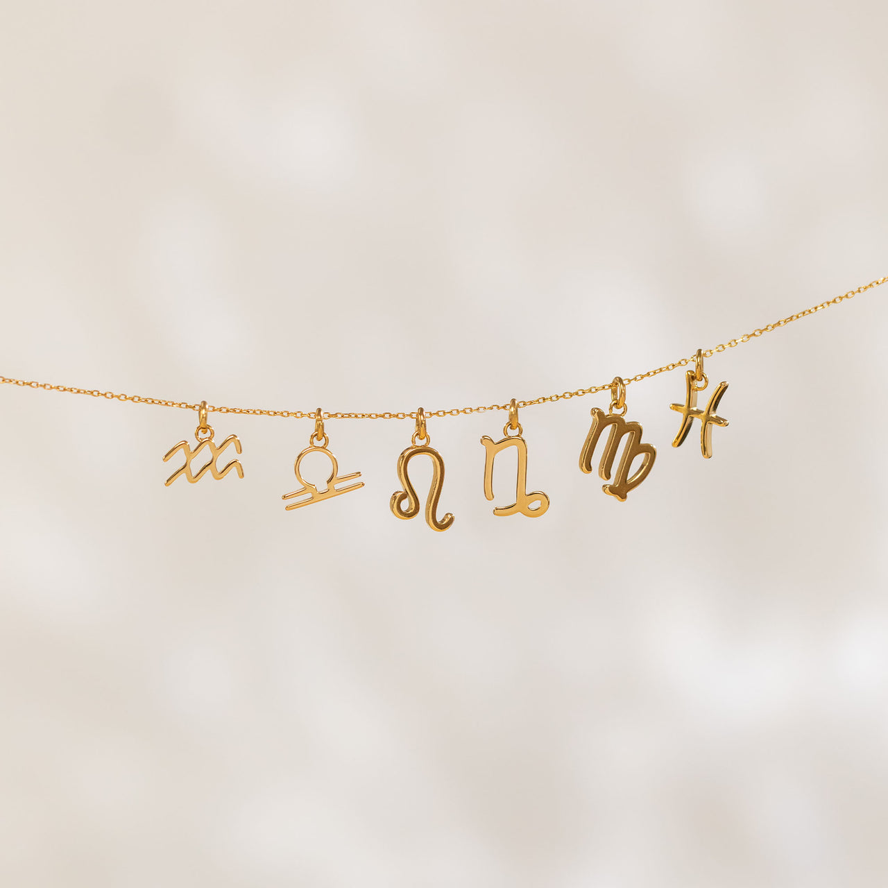 Waage Zodiac Charm von PURELEI, 18K vergoldet, filigran und elegant an einer feinen Kette schwebend.